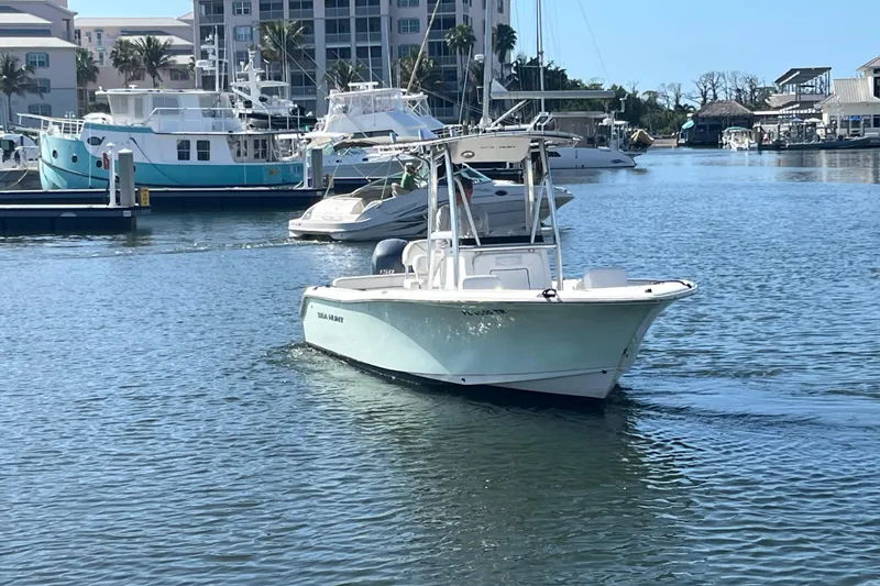 Slide: The Image of 2014 Sea Hunt Ultra 211 boat cruising in a marina with other vessels. - 2