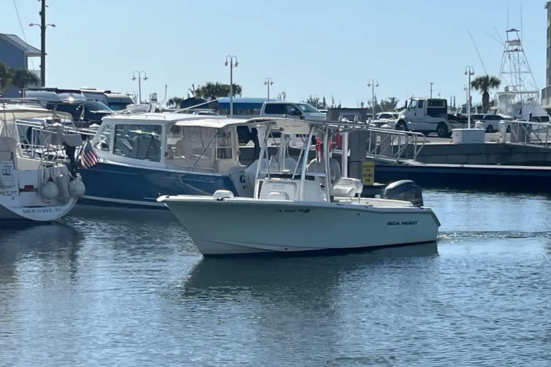 Slide: The Image of 2014 Sea Hunt Ultra 211 boat navigating marina waters, surrounded by other vessels. - 3