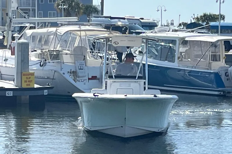Slide: The Image of 2014 Sea Hunt Ultra 211 boat navigating marina with other vessels docked nearby. - 4