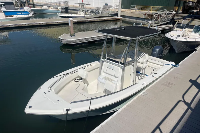 Slide: The Image of 2014 Sea Hunt Ultra 211 boat docked at marina, featuring a sleek design and T-top. - 9