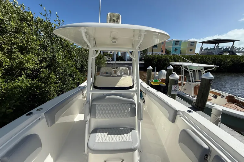 Slide: The Image of 2018 NauticStar 28 XS boat docked, featuring sleek seating and canopy, with colorful buildings in background. - 11