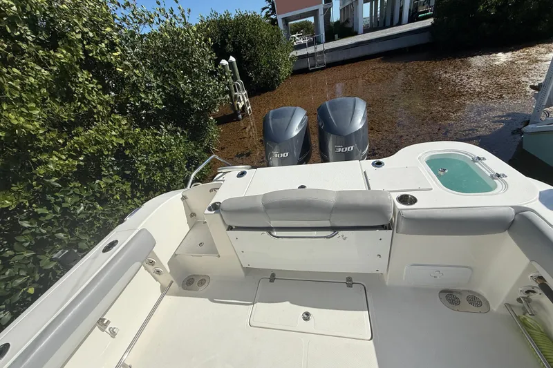 Slide: The Image of 2018 NauticStar 28 XS boat with dual engines, docked near lush greenery. - 13