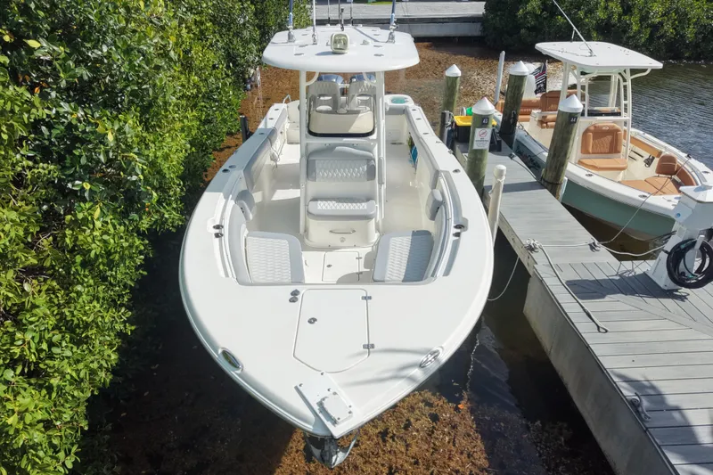 Slide: The Image of 2018 NauticStar 28 XS boat docked, aerial view, surrounded by greenery and water. - 2