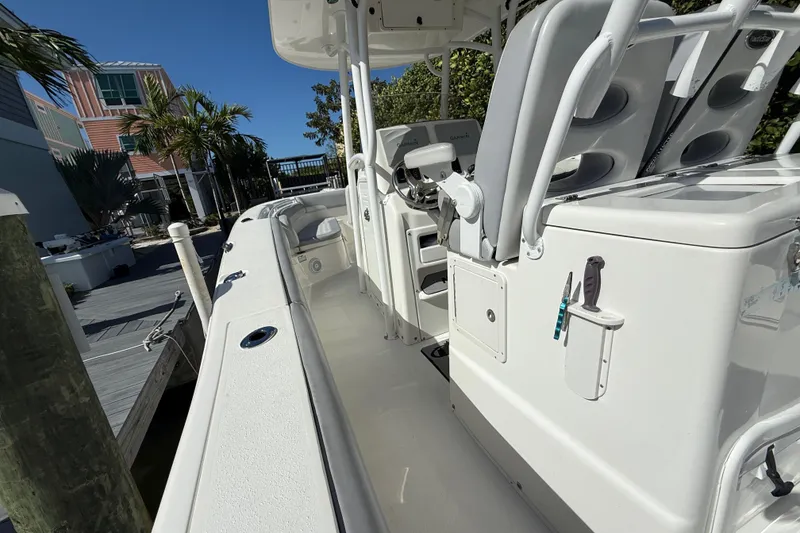Slide: The Image of 2018 NauticStar 28 XS boat interior with seating and console, docked near palm trees. - 24