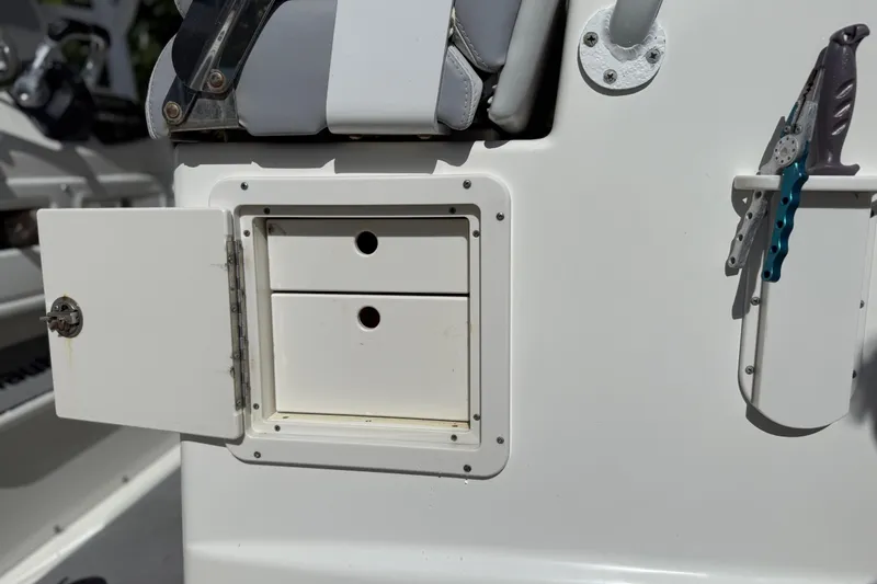Slide: The Image of 2018 NauticStar 28 XS boat storage compartment with open door and tool holder. - 27