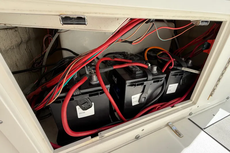 Slide: The Image of 2018 NauticStar 28 XS boat battery compartment with wiring and three batteries. - 40