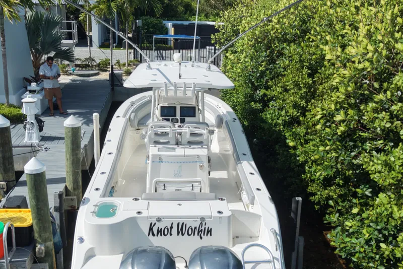 Slide: The Image of 2018 NauticStar 28 XS boat docked, surrounded by lush greenery. - 6