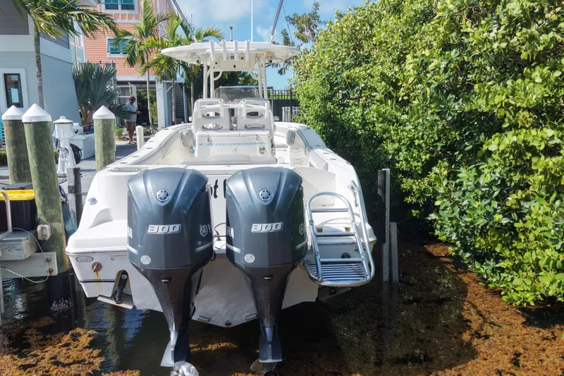 Slide: The Image of 2018 NauticStar 28 XS boat docked with dual Yamaha engines, surrounded by lush greenery. - 7