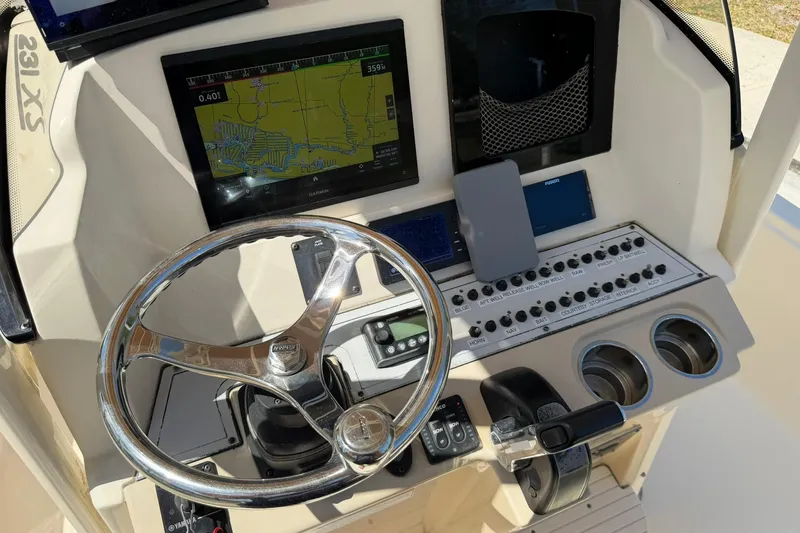 Slide: The Image of 2018 Scout 231 XS boat dashboard with steering wheel, navigation screen, and control panel. - 16