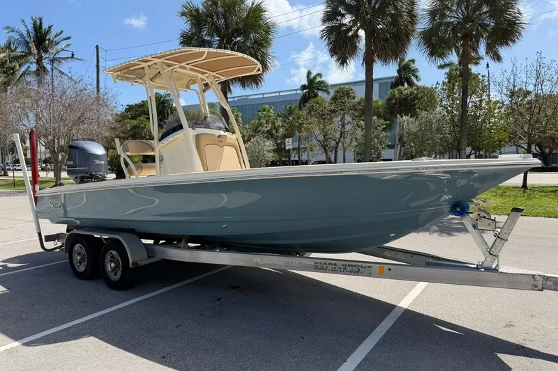 Slide: The Image of 2018 Scout 231 XS boat on trailer, parked under palm trees. - 7