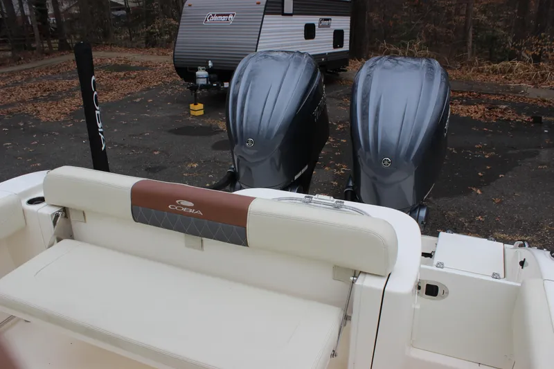 Slide: The Image of 2022 Cobia 280 Center Console boat with dual outboard engines in a parking area. - 24
