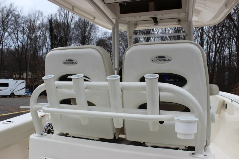 Slide: The Image of 2022 Cobia 280 Center Console boat seats with rod holders, parked outdoors. - 26