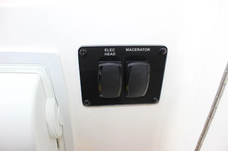 Slide: The Image of Control panel with switches for electric head and macerator on 2022 Cobia 280 Center Console. - 37
