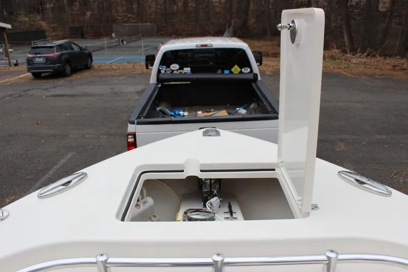 Slide: The Image of 2022 Cobia 280 Center Console boat with open storage compartment, parked near a pickup truck. - 45