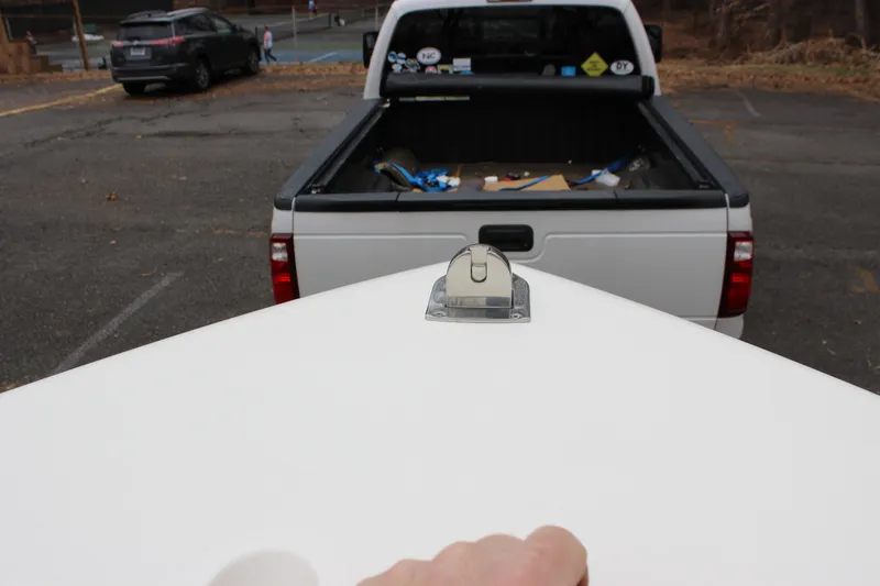 Slide: The Image of 2022 Cobia 280 Center Console boat bow near a parked pickup truck. - 47
