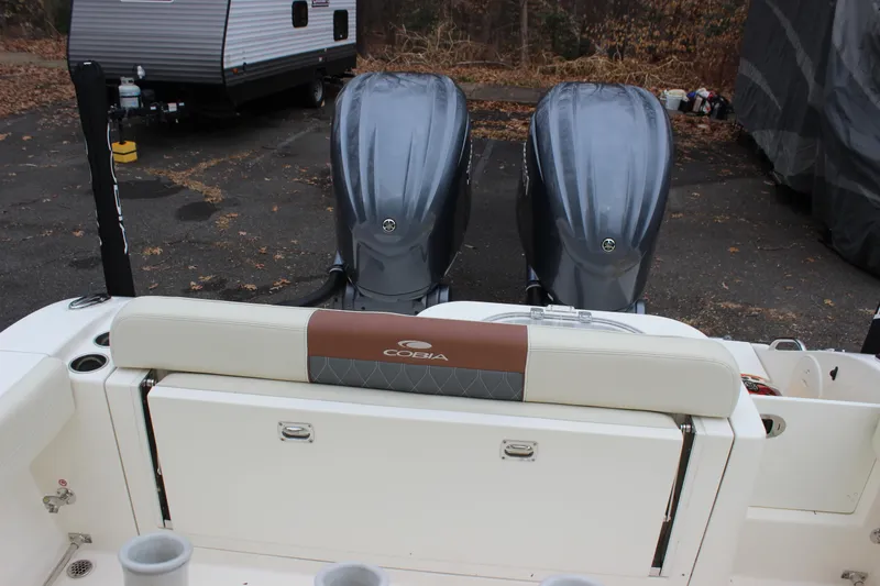 Slide: The Image of 2022 Cobia 280 Center Console boat with dual engines, parked near a trailer. - 62