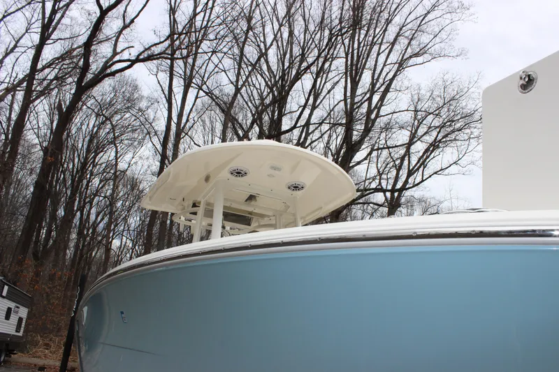 Slide: The Image of 2022 Cobia 280 Center Console boat with blue hull, docked near leafless trees. - 7