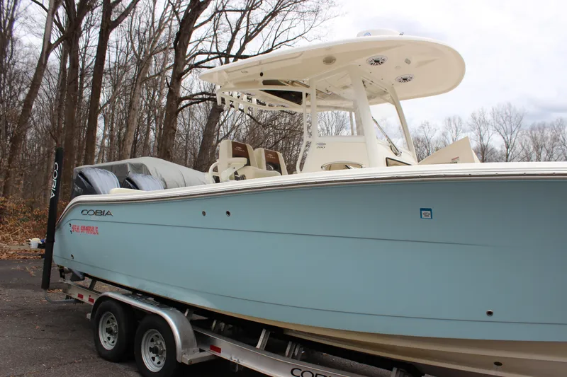 Slide: The Image of 2022 Cobia 280 Center Console boat on trailer in wooded area. - 8