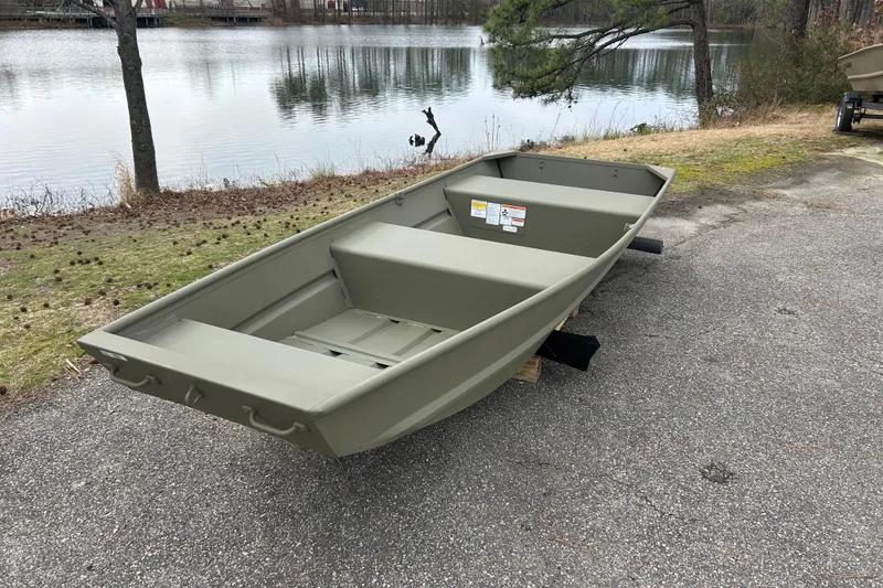 Slide: The Image of 2026 Tracker Grizzly 12 Jon boat by a serene lake. - 2