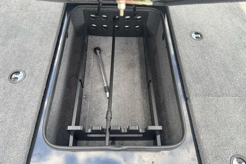 Slide: The Image of Open storage compartment in 2026 Ranger ALPHA 208 boat, featuring carpeted interior and rod holder. - 80