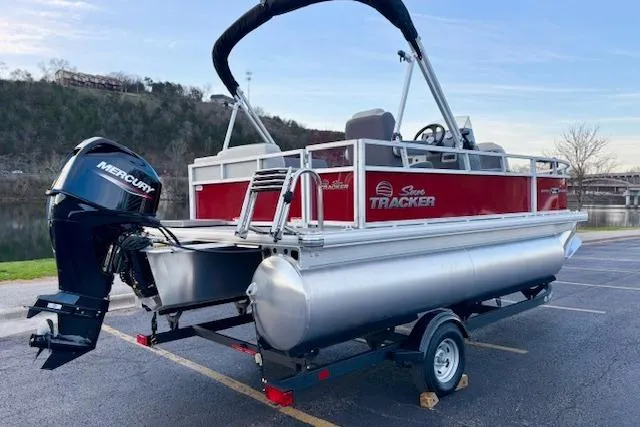 Slide: The Image of 2026 Sun Tracker Bass Buggy 16 XL Select pontoon boat with Mercury engine, parked outdoors. - 97
