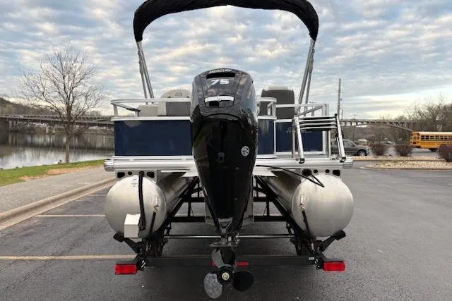 Slide: The Image of 2026 Sun Tracker Bass Buggy 18 DLX pontoon boat with 75 HP engine, parked by a lake. - 100