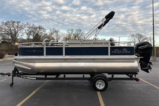 Slide: The Image of 2026 Sun Tracker Bass Buggy 18 DLX pontoon boat on trailer, parked outdoors. - 101