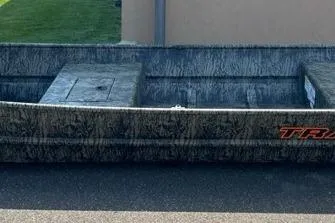 The Image of 2026 Tracker Grizzly 15 Jon boat with camouflage design, parked outdoors. - 0