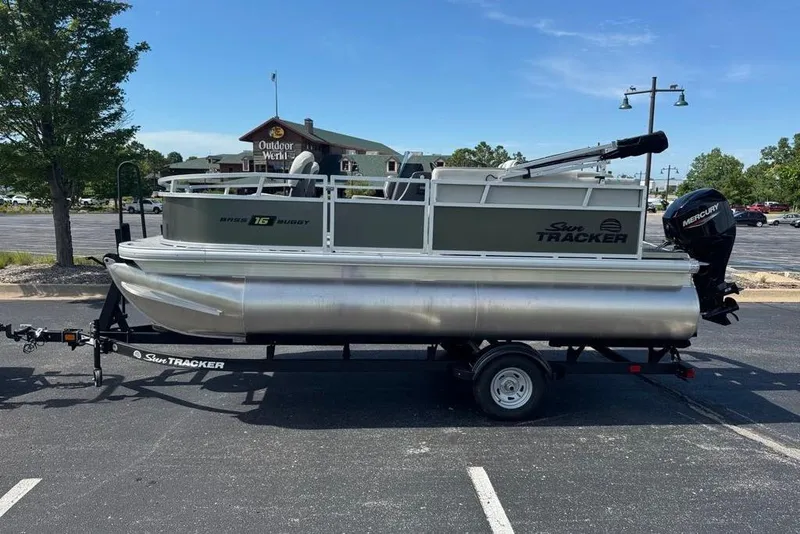 Slide: The Image of 2026 Sun Tracker Bass Buggy 16 XL Select pontoon boat on trailer in parking lot. - 1