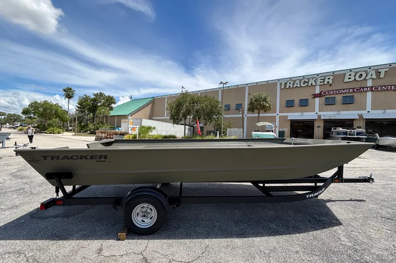 The Image of 2026 Tracker Grizzly 2072 Utility boat on trailer outside dealership under blue sky. - 0