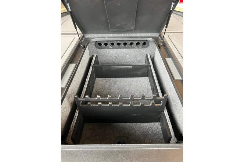 Slide: The Image of Open storage compartment in 2026 Tracker Savage 215 boat, featuring rod holders and organized space. - 14