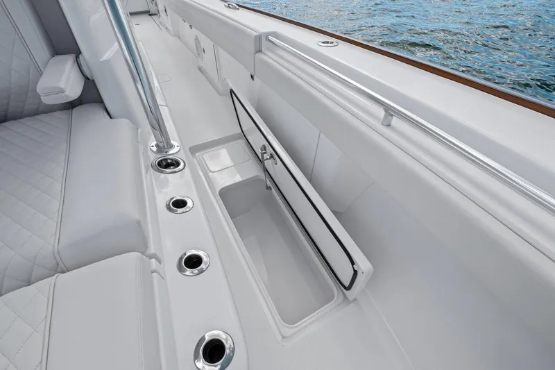Slide: The Image of 2026 Valhalla Boatworks V-37 interior with storage compartment and rod holders, near water. - 20
