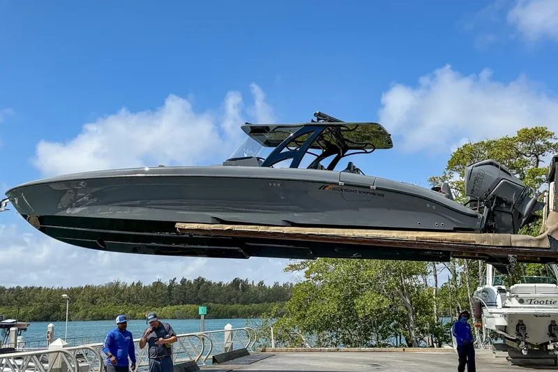 Slide: The Image of 2023 Midnight Express 43 Solstice boat being lifted at a marina under a clear blue sky. - 53