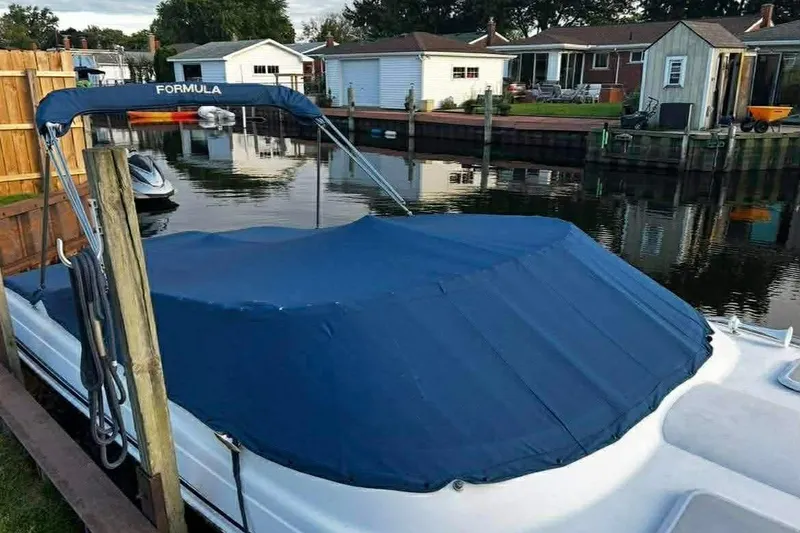 Slide: The Image of 2005 Formula 260 Sun Sport boat with blue cover docked by waterfront homes. - 2