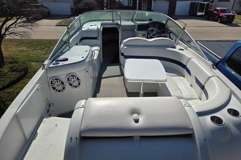 Slide: The Image of 2005 Formula 260 Sun Sport boat interior with seating and table, parked in a residential area. - 6