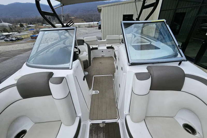 Slide: The Image of 2013 Yamaha Boats 242 Limited interior with seating and open windshield, docked outdoors. - 5