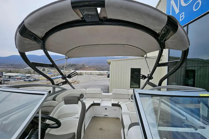 Slide: The Image of 2013 Yamaha Boats 242 Limited interior with seating and canopy, parked near a building. - 4
