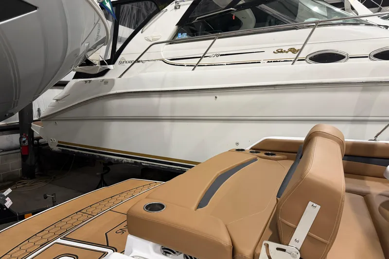 Slide: The Image of 2025 Four Winns HD3 boat interior with tan seating, docked beside a white yacht. - 14