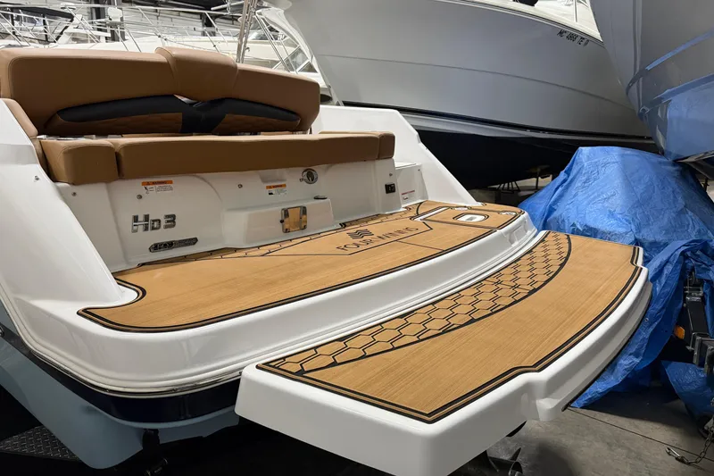 Slide: The Image of 2025 Four Winns HD3 boat with teak deck and cushioned seating in a showroom. - 15