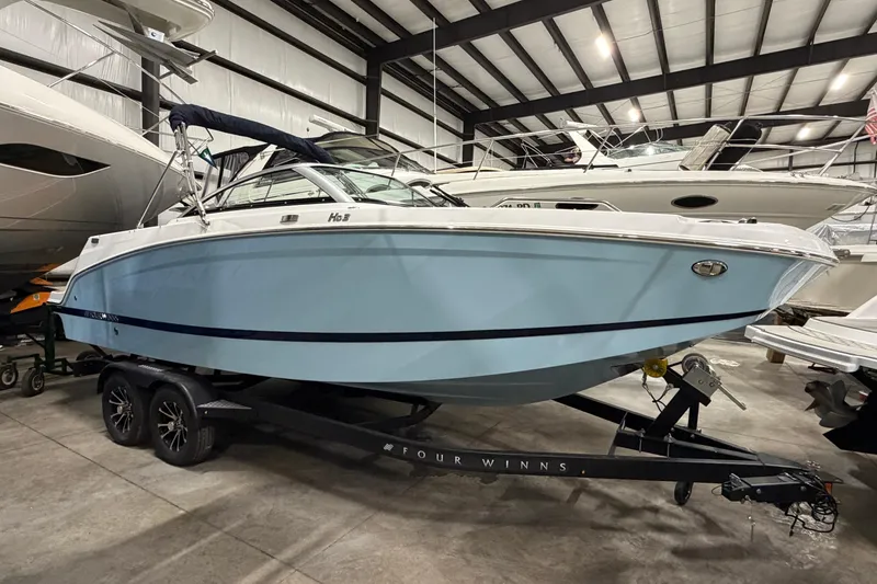Slide: The Image of 2025 Four Winns HD3 boat in a showroom, light blue hull on a trailer. - 5
