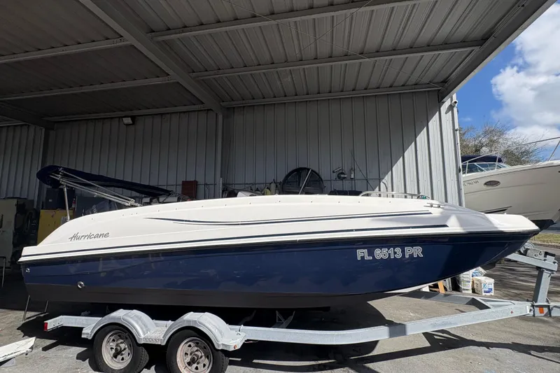 Slide: The Image of 2014 Hurricane SunDeck 187 OB boat with outboard motor and canopy in covered storage. - 6
