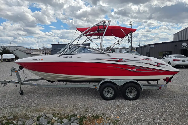 Slide: The Image of 2005 Yamaha AR230 boat with red and white design on a trailer, parked outdoors. - 2