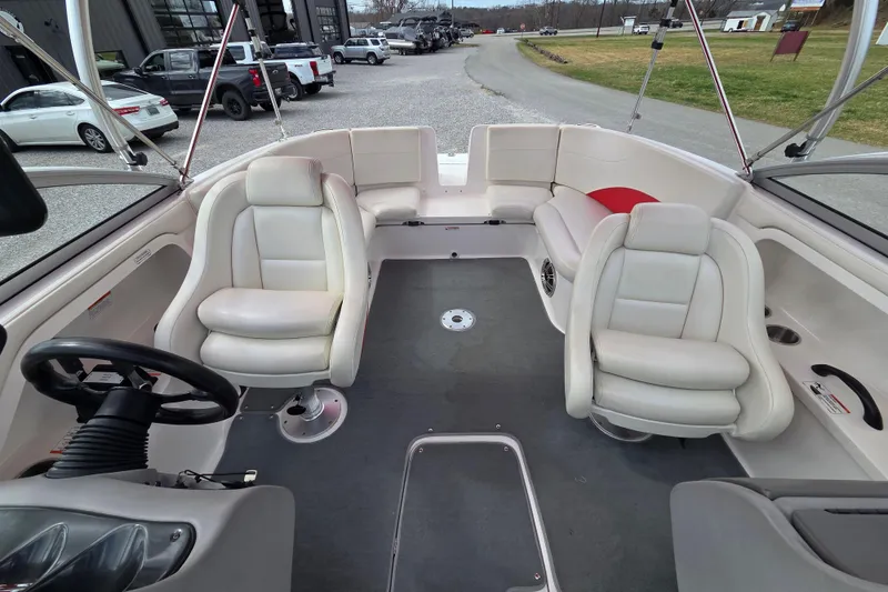 Slide: The Image of 2005 Yamaha Boats AR230 interior with white seating and steering wheel, parked outdoors. - 9