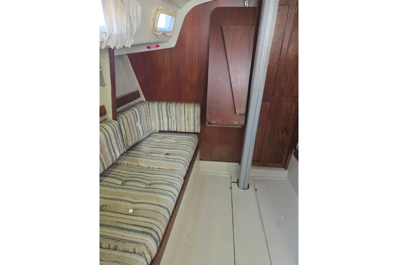 Slide: The Image of Interior of 1982 O'Day 28 sailboat with striped seating and wooden cabinetry. - 13