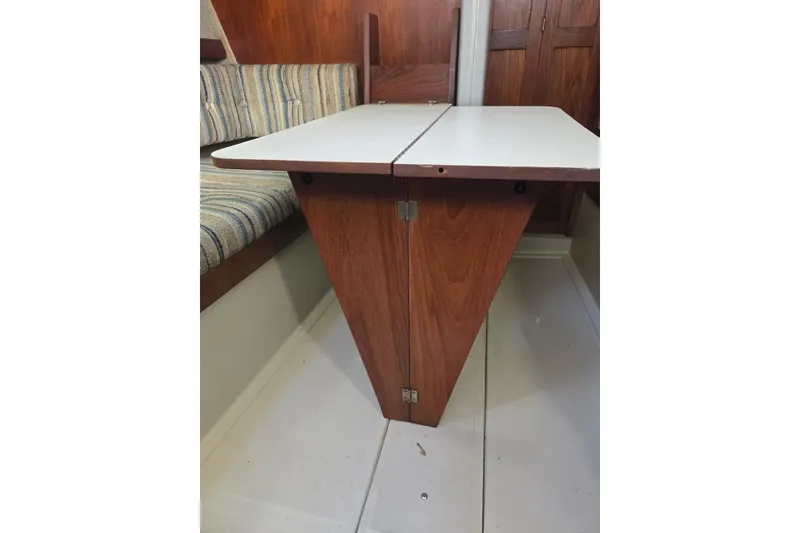 Slide: The Image of 1982 O'Day 28 sailboat interior with foldable wooden table and striped seating. - 15