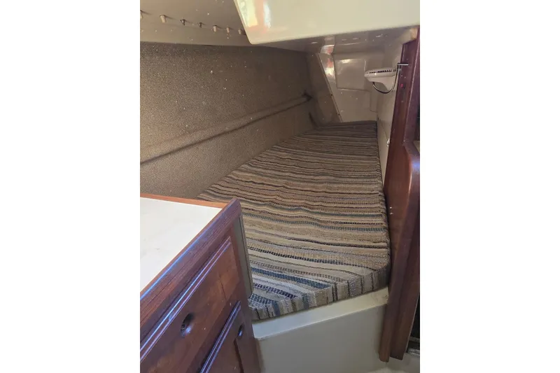 Slide: The Image of 1982 O'Day 28 sailboat interior cabin with striped bedding and wooden cabinetry. - 17