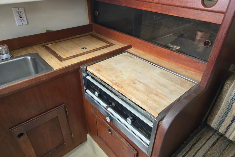 Slide: The Image of 1982 O'Day 28 sailboat galley with wooden countertops and built-in stove. - 22
