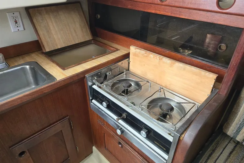 Slide: The Image of 1982 O'Day 28 sailboat galley with stove, sink, and wooden cabinetry. - 23