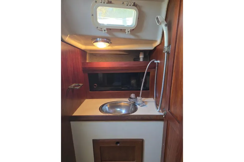 Slide: The Image of 1982 O'Day 28 sailboat interior with sink, wooden cabinetry, and porthole window. - 35