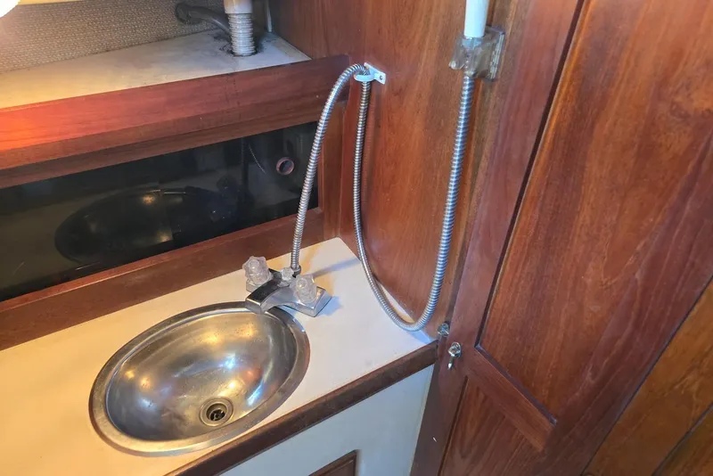 Slide: The Image of 1982 O'Day 28 sailboat interior sink with wooden cabinetry and flexible faucet. - 36